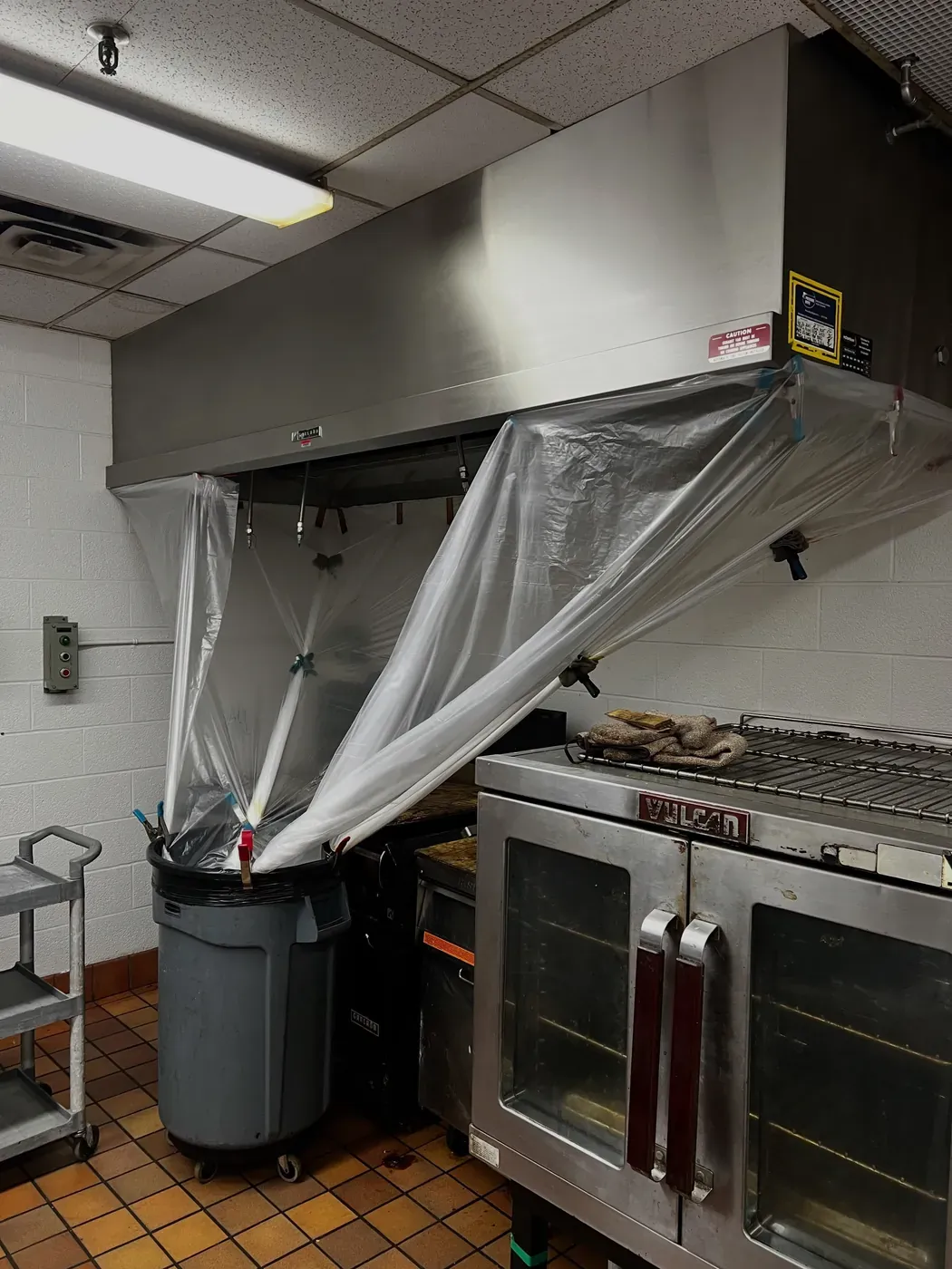 Kitchen hood and cooking line wrapped in plastic sheeting by the crew before a cleaning